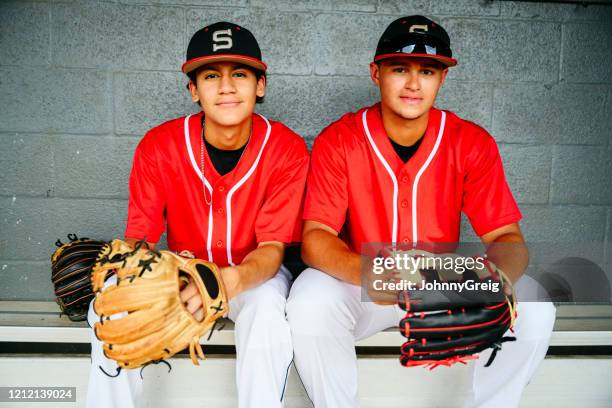 retrato de jogadores hispânicos de beisebol com luvas em dugout - uniforme de equipe - fotografias e filmes do acervo