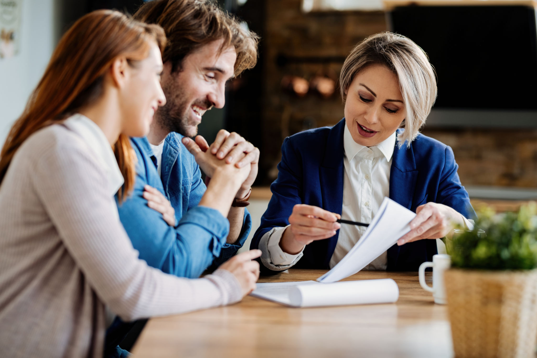 Happy couple and their insurance agent analyzing paperwork during a meeting. Happy couple and their insurance agent analyzing paperwork during a meeting.