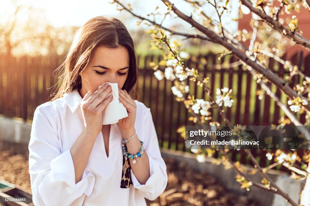 Woman sneezing in the blossoming garden