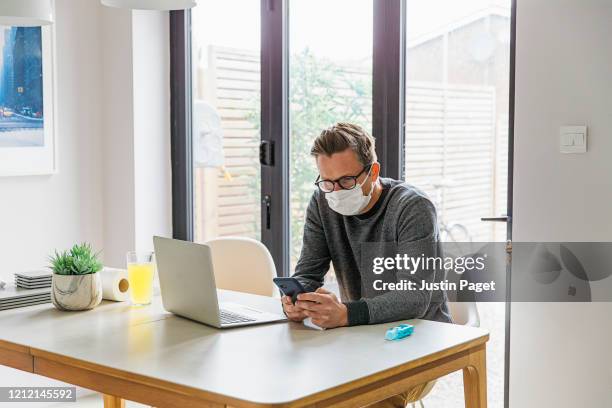 man working from home. using smartphone - covid-19 quarantine stock pictures, royalty-free photos & images