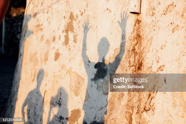 shadows of young men on medieval village wall - stone wall stock pictures, royalty-free photos & images