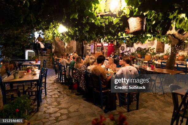 groupe d’amis mangeant le dîner dans la cour méditerranéenne - crète photos et images de collection