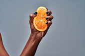 Female hand squeezing orange isolated on grey