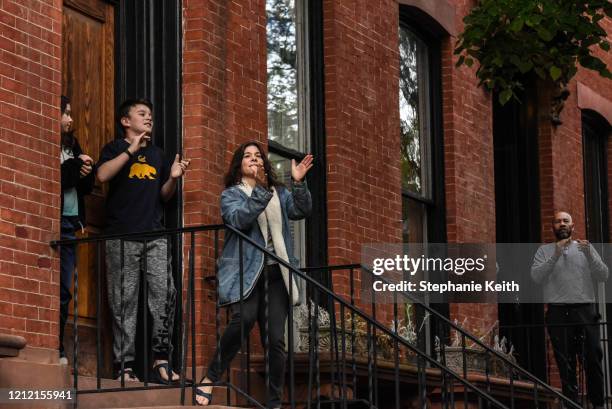 Residents living under lockdown rules stand on their stoops to celebrate medical workers on May 7, 2020 in the Clinton Hill neighborhood in the...