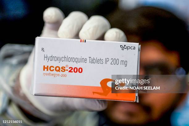 This photo taken on April 28, 2020 shows a pharmacist displaying a box of hydroxychloroquine tablets in his store in Hyderabad. - India has ramped up...