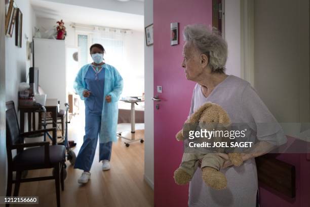 Nicole Muller exits her room holding her rabbit plush toy "Jeannot" at the Camille Saint-Saens EHPAD in Aulnay-sous-Bois, a Paris suburb, on May 6 on...