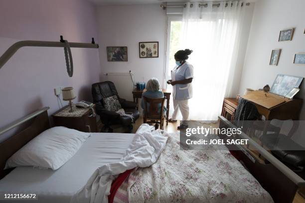 Nurse speaks to a resident in her bedroom at the Camille Saint-Saens EHPAD in Aulnay-sous-Bois, a Paris suburb, on May 6 on the 51st day of a strict...