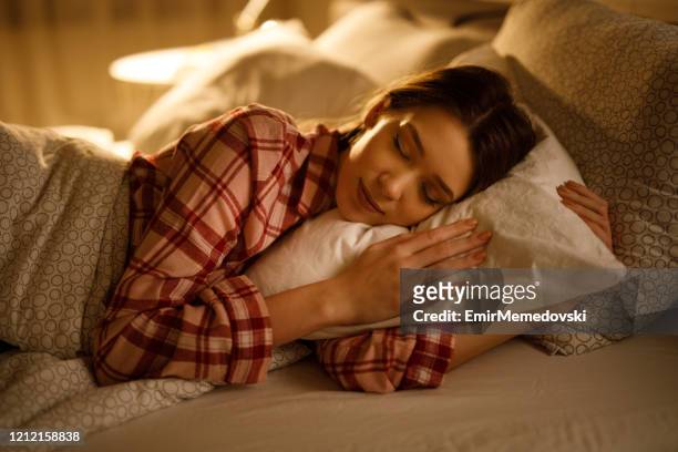 woman sleeping in bed hugging soft white pillow - positive emotion stock pictures, royalty-free photos & images