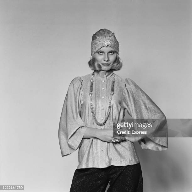 British model and actress Suzy Miller wearing a Lurex blouse with angel sleeves, a turban, and a long necklace, for a studio fashion shoot, 15th...