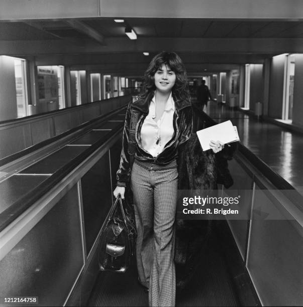 French actress Maria Schneider , carrying documents in one hand, a holdall in the other, a fur coat over her arm, as she walks through Heathrow...