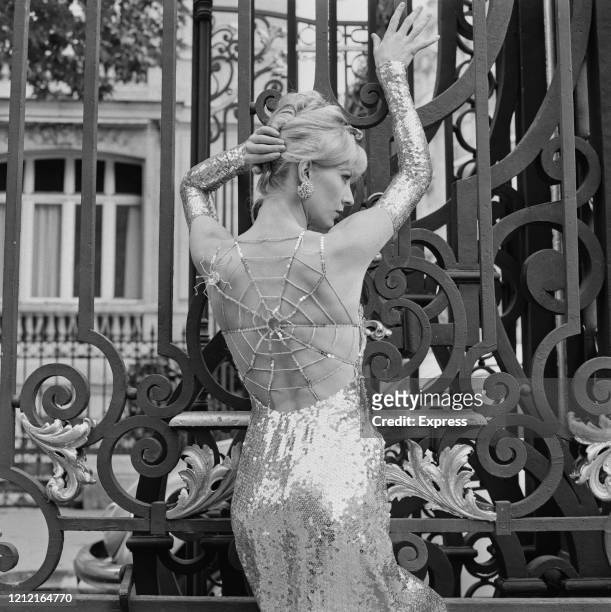 British actress and model Vicki Hodge wearing a silver and crystal spider sequin evening dress by Loris Azzaro, with a spider's web design across the...