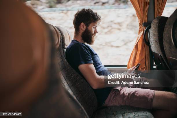 es gibt so viel, was mich auf dieser langen reise beschäftigt - mann bus smartphone stock-fotos und bilder