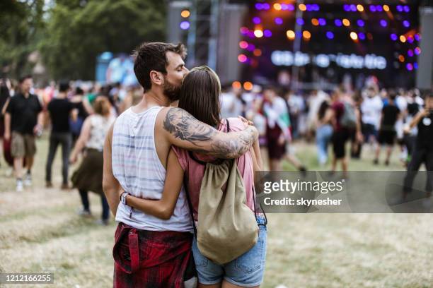 rear view of a loving couple embracing while enjoying in music concert. - couple concert stock pictures, royalty-free photos & images