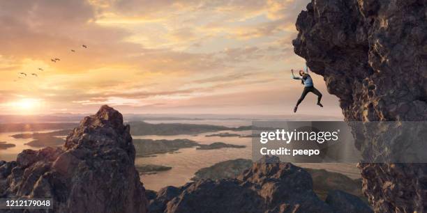 female extreme free climber ascends steep rock face at sunset - überhängend stock-fotos und bilder