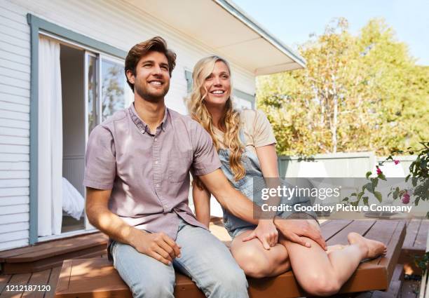 smiling young couple sitting together on their backyard patio at home - backyard deck stock pictures, royalty-free photos & images