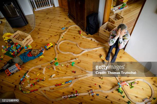 Symbol picture on the topic of single parent. A mother is sitting desperately on the floor while her child is playing among toys on May 04, 2020 in...