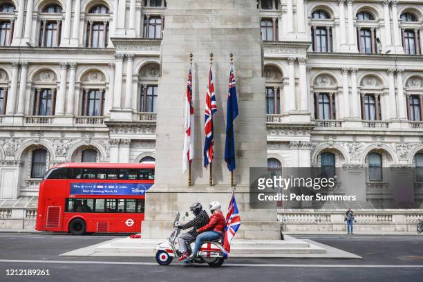 Couple on a moped adorned with Union Jacks pass in front of the Cenotaph on May 8, 2020 in London, United Kingdom.The UK commemorates the 75th...