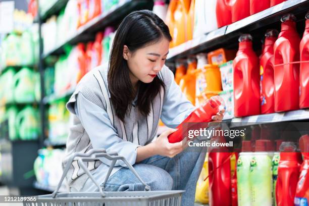 asian woman buys washing powder in supermarket - wasmiddel stockfoto's en -beelden