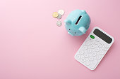 Piggy bank, calculator and coins on pink background