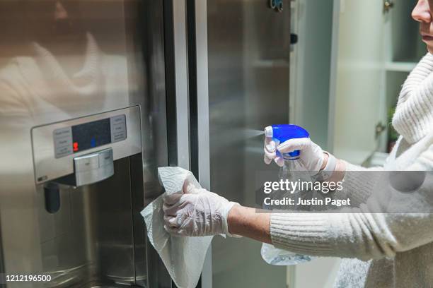 woman disinfecting fridge handle - fridge handle stock pictures, royalty-free photos & images