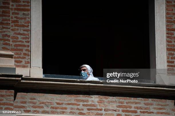 Nun nurse of the Padua Hospital looking out onto the balcony of the Ancient Cloister wears a protective mask, Padua, 8th May 2020