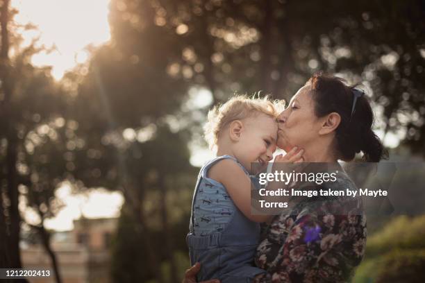 toddler holding grandma's face while she kisses him - fashionable grandma stock pictures, royalty-free photos & images