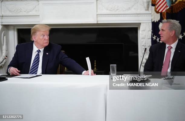 President Donald Trump holds up a note to US representative Kevin McCarthy as he meets with Republican members of the US Congress in the State Dining...