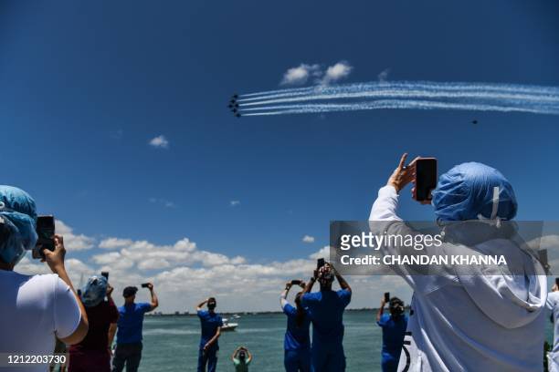 Health care workers gather by the bay to watch the US Navy Blue Angels and US Air Force Thunderbirds fly over the Mount Sinai Medical Center in...