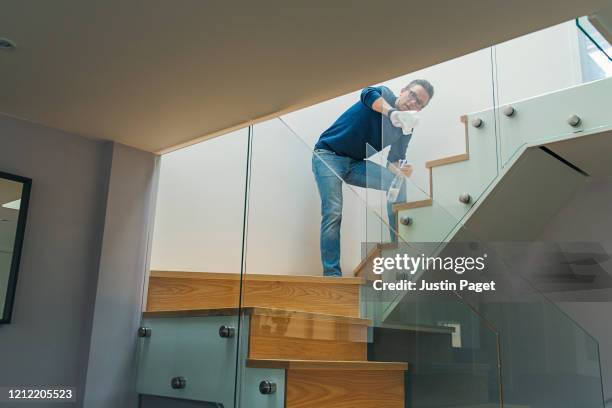 man disinfecting glass on staircase - ballustrade stockfoto's en -beelden