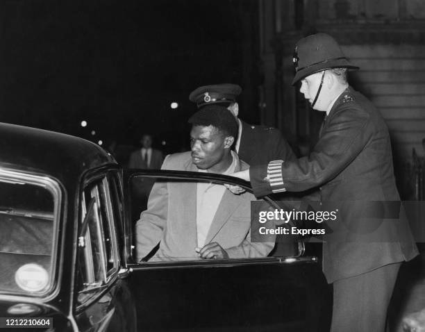 Two police officers take off a man in a police car during the Notting Hill race riots, London, UK, 2nd September 1958.