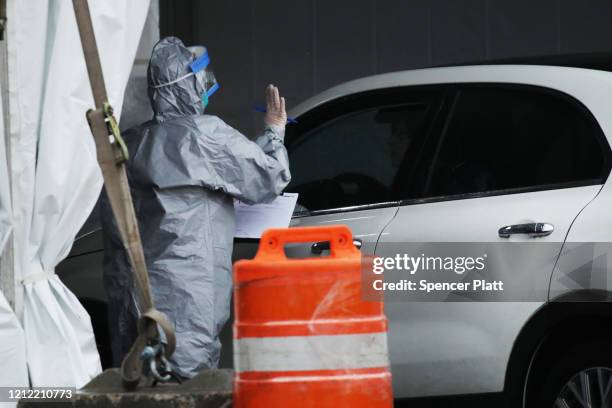 Workers in protective gear operate a drive through COVID-19 mobile testing center on March 13, 2020 in New Rochelle, New York. The center serves all...