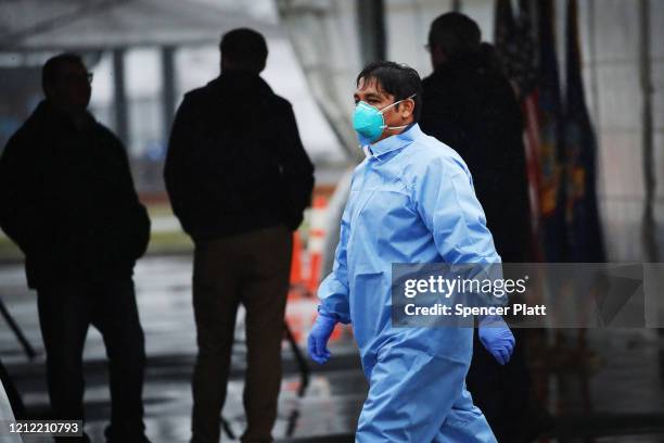 Workers in protective gear operate a drive through COVID-19 mobile testing center on March 13, 2020 in New Rochelle, New York. The center serves all...