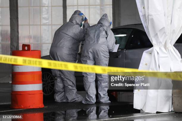 Workers in protective gear operate a drive through COVID-19 mobile testing center on March 13, 2020 in New Rochelle, New York. The center serves all...