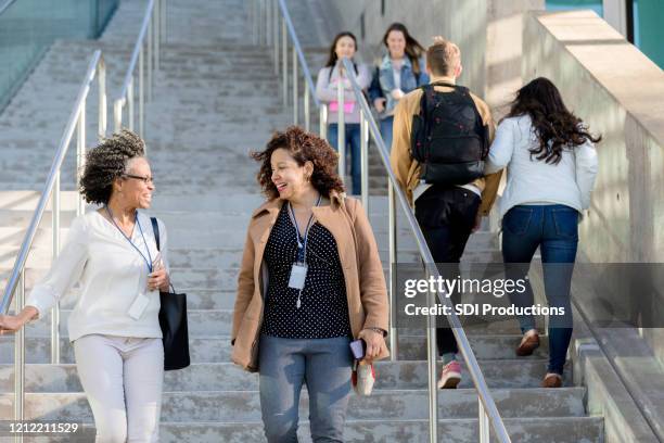 female college professors walk together on campus - community college stock pictures, royalty-free photos & images