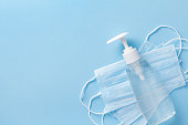 Sanitizer gel or antibacterial soap and face mask for coronavirus preventive measure, top view.