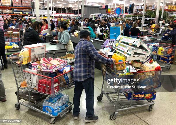 Costco customer stands by his two shopping carts at a Costco store on March 13, 2020 in Richmond, California. Some Americans are stocking up on food,...