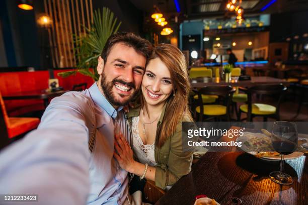 cheerful couple smiling while taking selfie - romantic dining stock pictures, royalty-free photos & images