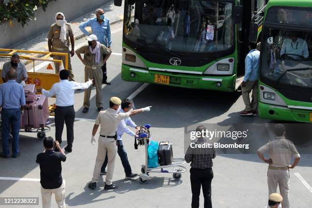 Passengers of an Air India Ltd. Repatriation flight from Singapore are escorted to buses, destined for quarantine centers, at the Indira Gandhi...