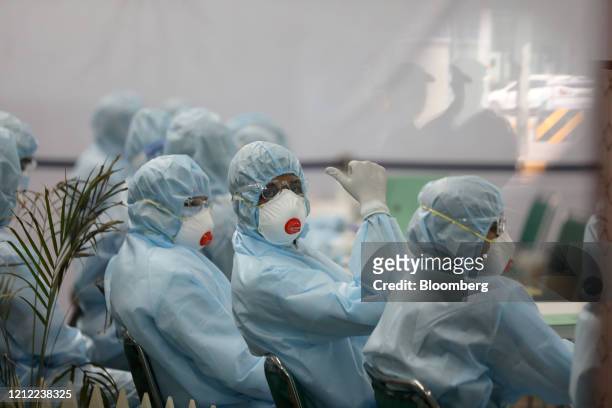 Health care workers wearing personal protective equipment wait to speak to a passengers recently arrived on an Air India Ltd. Repatriation flight...
