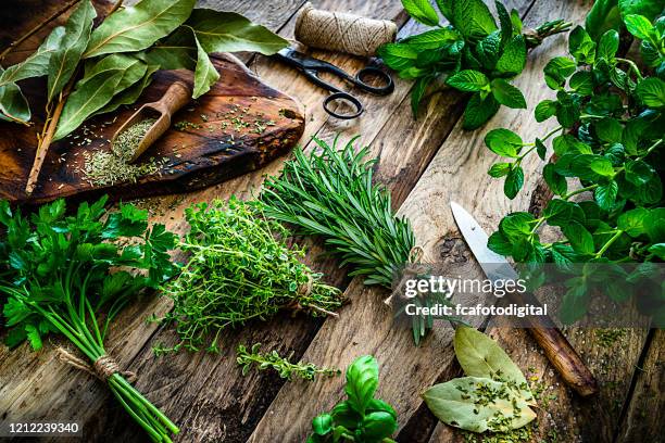 färska doftande ekologiska örter för matlagning skott på rustikt köksbord - herb bildbanksfoton och bilder