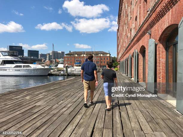 father and son walking along the waterfront - baltimore waterfront stock pictures, royalty-free photos & images