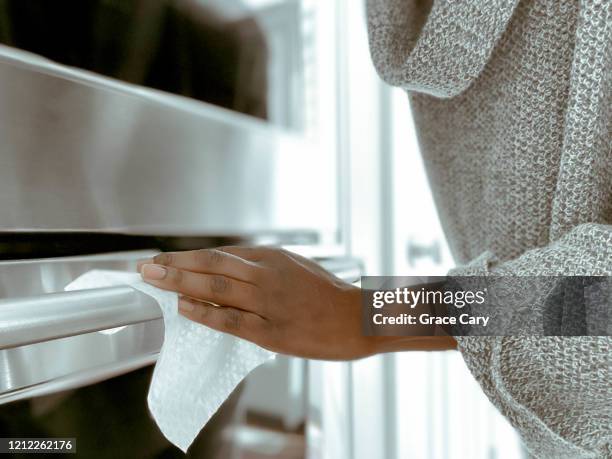 woman cleans oven handle using disinfectant wipe - clean kitchen stock pictures, royalty-free photos & images