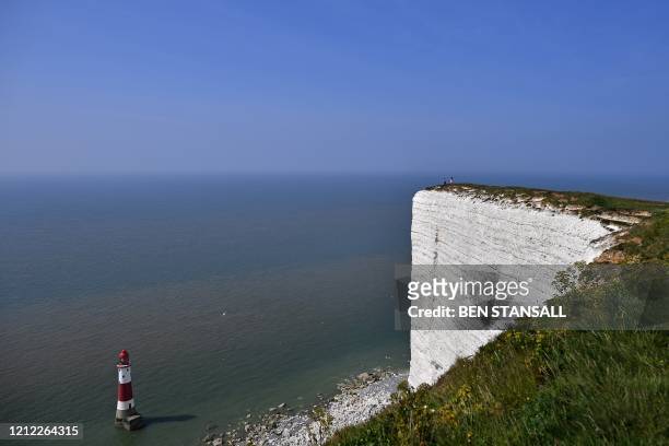People sit on the cliffs at Beachy Head, near Eastbourne, southern England on May 9 as life in Britain continues over the May bank holiday weekend,...