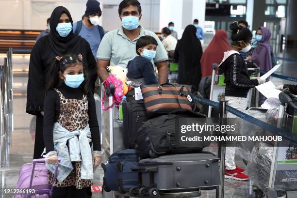 Members of an Indian family check in at the Muscat International Airport before leaving the Omani capital on a flight to return to their country, on...