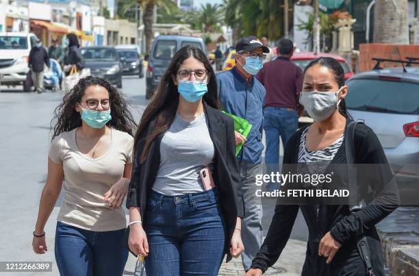 Tunisians wearing protective masks amid the COVID-19 pandemic walk by on as street in the Kram area of the capital Tunis on May 8 as authorities...