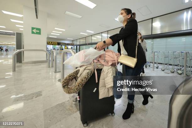 Passenger wearing a protective mask carries luggage after arriving at Mexico City airport on March 13, 2020 in Mexico City, Mexico. Mexican peso,...