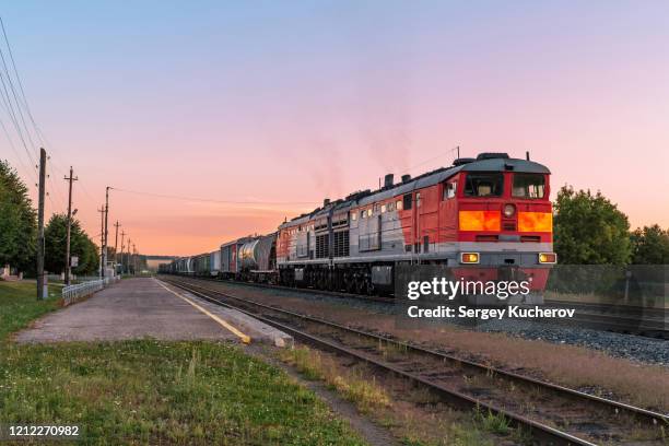 powerful diesel locomotive with a heavy freight train in a beautiful sunset light - 貨物列車 ストックフォトと画像