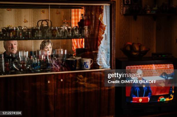 Gennady Matveiev with his wife Galina watch the television screen showing Russian President Vladimir Putin's address to the nation marking the 75th...
