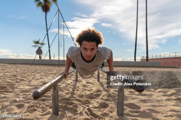 the young latino man doing push-up exercise on the bars - bodyweight training stock pictures, royalty-free photos & images