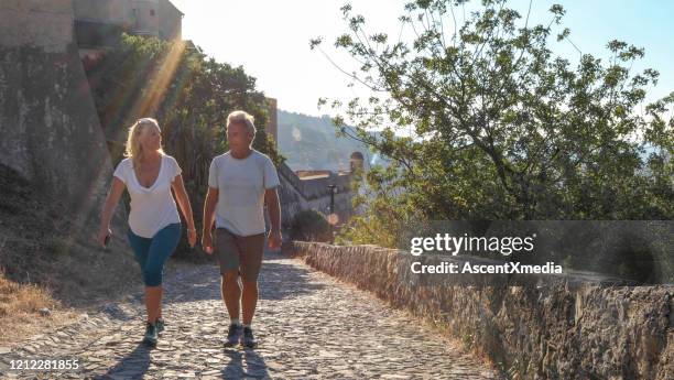 reifes paar wandern kopfsteinpflasterweg bei sonnenaufgang - dorf oben stock-fotos und bilder